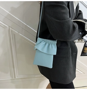 Détail du mini sac bandoulière bleu clair avec bordure à volants et texture grainée