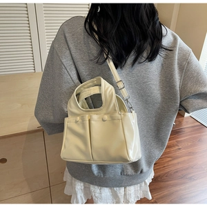 Cream white mini tote bag worn by model, showing dual pockets and adjustable strap