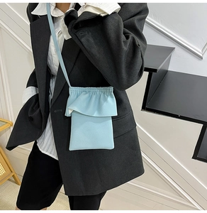 Mini sac bandoulière bleu clair à volants et cuir grainé porté avec un blazer noir