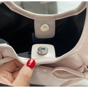 Close-up of light pink glossy handbag showing magnetic closure and interior lining
