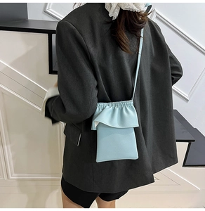 Gros plan d'un mini sac bandoulière bleu clair avec bordure à volants et grain litchi