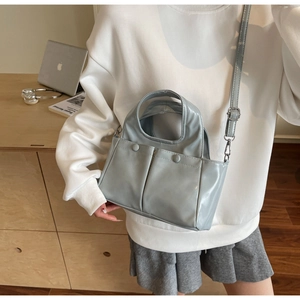 Close-up of light blue vintage tote bag with dual front pockets and glossy PU texture