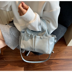 Close-up of light blue pleated tote bag with dual front pockets and shoulder strap