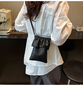 Détail du sac bandoulière en cuir grainé noir avec fermeture plissée style nuage chic