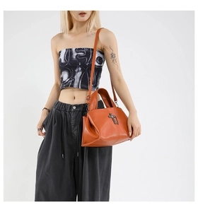 Detail of orange brown pebble leather tote bag with vintage metal cross ornament