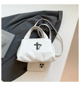 Detail of white lychee leather tote bag featuring gothic metal cross and chain ornaments