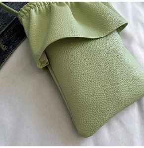 Détail du petit sac de téléphone vert clair avec texture litchi et design plissé chic