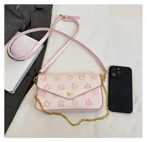 Pink cartoon crossbody bag size comparison with smartphone and golden chain detail