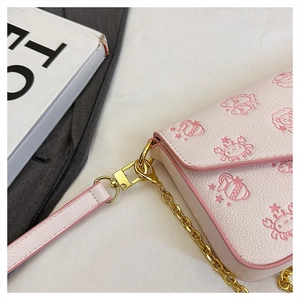 Detail of pink crossbody bag featuring zodiac crab prints and gold chain hardware