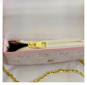 Detail of a smooth golden zipper on a cream leather bag with pink trim and embossed pattern