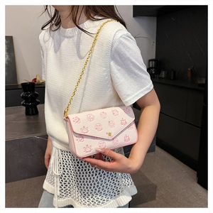 Pink chain crossbody bag with cartoon zodiac patterns and golden strap on a model