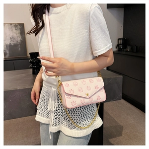 Close-up of pink and white chain crossbody bag with cartoon illustrations and metal chain