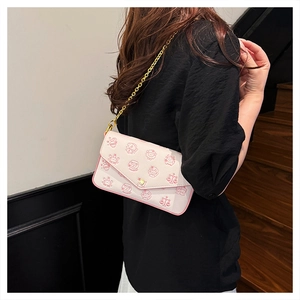 Detail view of pink patterned crossbody chain bag with golden clasp worn by a model