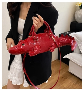 Macro view of red 3D crocodile handbag showing glossy patent leather and embossed texture