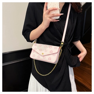Detail of crossbody bag with pink cartoon motifs and golden metal chain strap