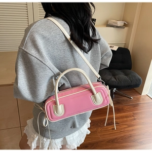 Detail of pink baguette bag with contrast cream strap and side knot tassel ties