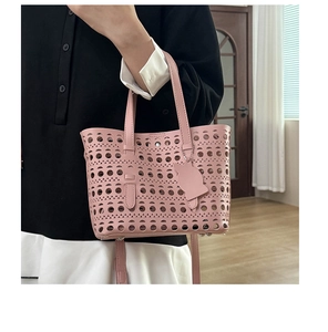 Detail of pink laser-cut hollow tote bag featuring a cute cat-shaped leather charm tag