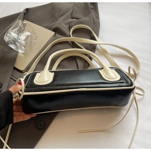 Detail of contrast stitching on black leather bag with beige straps and zipper closure