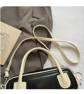Dettaglio borsa baguette bicolore con finiture metalliche su giacca grigia