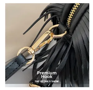 Close-up of high-quality golden metal hook and fringe detail on black crossbody bag