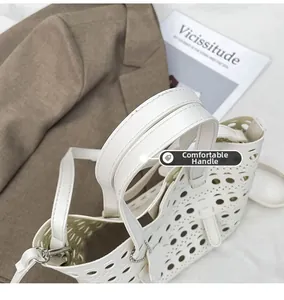Detail of laser-cut white leather tote featuring dual handles and metallic hardware