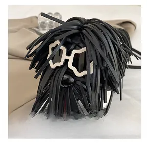 Detail showing black fringe dog-shaped crossbody bag with white frame sunglasses
