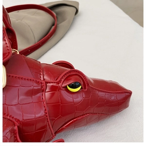 Close-up of a red crocodile-shaped handbag with yellow eye detail and realistic scale texture