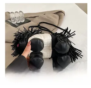 Detail showing durable base feet and long black tassels on the quilted dog-shaped bag