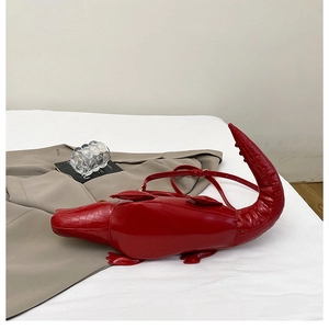 Macro shot of 3D crocodile-shaped bag in bright red faux leather with textured embossing
