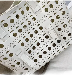 Detail of laser-cut geometric patterns on white leather shoulder bag surface