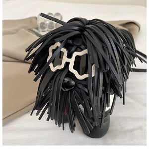 Detail of dog-shaped crossbody bag featuring long black tassels and sunglasses hardware