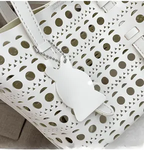 Close-up of white laser-cut hollow leather tote bag with a cute rabbit charm detail