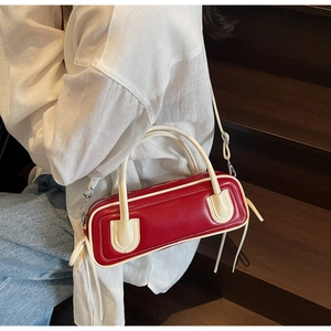 Detail of red and cream contrast bowling bag with tassel charm and adjustable strap