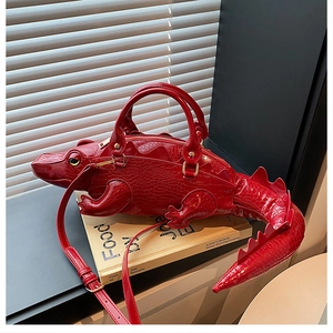 Close-up of red crocodile-shaped handbag with glossy embossed texture and gold hardware