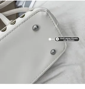 Detailed macro view of white leather bag bottom featuring silver anti-wear metal rivets