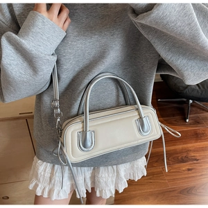 Detail view of cream white and silver rectangular baguette bag with adjustable strap
