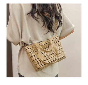 Detail of laser-cut hollow pattern and protective bottom studs on the khaki tote bag