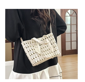 Detail of white hollowed-out tote bag featuring geometric laser-cut patterns and tulip charm