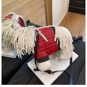 Detail of red quilted dog-shaped crossbody bag with white fringe and black strap