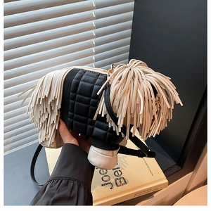Detail of creative dog-shaped crossbody bag with black quilted fabric and white tassels
