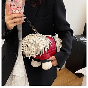 Close-up of red quilted crossbody bag featuring long white fringe dog design and gold buckles
