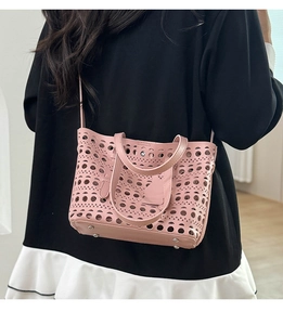 Detail of pink hollow-out tote bag with laser-cut patterns and metal bottom rivets