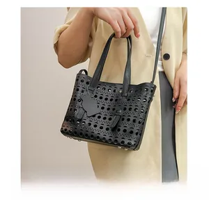 Detail of black laser-cut hollow leather bag with cat charm and geometric hole pattern