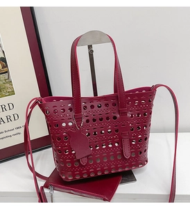 Detail of burgundy hollow-out tote bag with laser-cut patterns and cat charm
