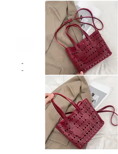 Detailed view of burgundy cutout tote bag with cat charm and adjustable shoulder strap