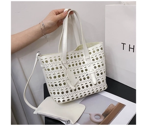 Detail view of white laser-cut hollow tote bag with matching inner pouch and shoulder strap