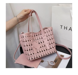 Detailed laser-cut hollow design on pink faux leather handbag with cat charm accessory