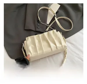Close-up of cream ruched cloud bag featuring metal chain and woven texture details