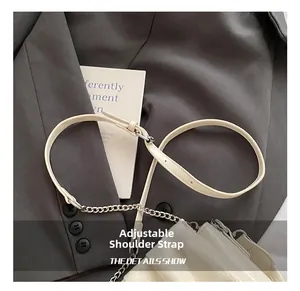 Detail of adjustable cream white lychee leather shoulder strap with silver metal chain