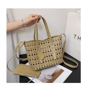 Detail of laser-cut hollow beige tote bag with inner pouch and cat charm on handle